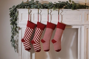 Close-up of four red and white striped knitted Christmas stockings on a white fireplace