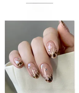 Detail of almond false nails with pink flower art, brown marble texture, and tiny rhinestones