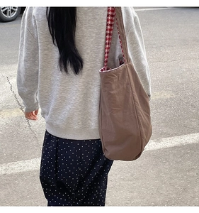 Close-up of a large brown wool tote bag featuring a red and white checkered lining