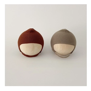 Detailed knit texture of infant earflap hats in reddish brown and taupe colors