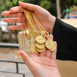 Macro shot of multiple 18K gold plated zodiac coin pendants with twisted rope chains