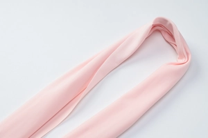 Detail of a pink knitted fabric ribbon showing soft texture and fine stitching on white background