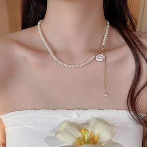 Detail of camellia flower pearl necklace with golden tassels worn on female neck