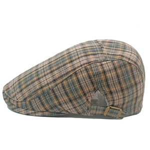 Détail de la casquette gavroche à carreaux avec boucle métallique et texture du tissu