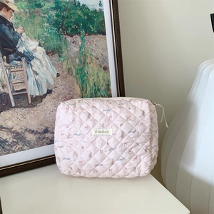 Sac de rangement matelassé rose avec motifs ours et nœuds sur table blanche