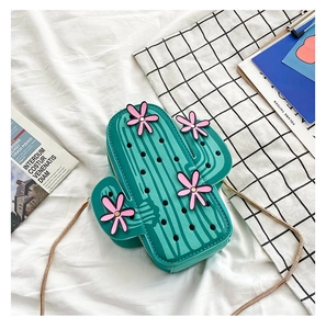 Detail view of green cactus-shaped crossbody bag with pink flowers and gold chain strap