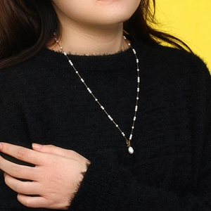 Close-up of 18K gold-plated chain with baroque pearls worn over a black sweater