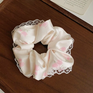 Gros plan du chouchou en satin à fleurs avec bordure en dentelle blanche délicate