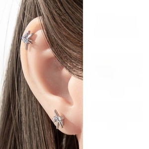 Close-up of star-shaped silver zircon stud earring worn on the cartilage and earlobe