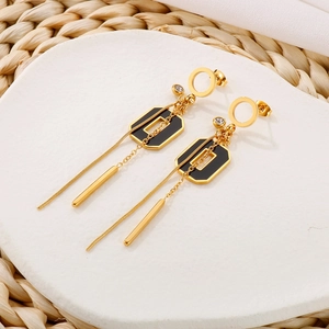 Détail de boucles d'oreilles pendantes dorées avec émail noir et accents de zircon
