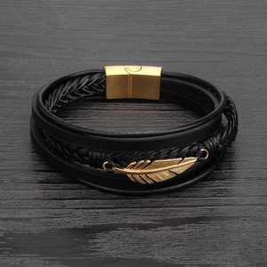 Detailed macro view of black braided leather layers with golden feather and magnetic clasp