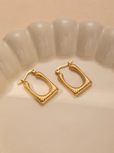 Detailed macro view of gold-plated rectangular hoop earrings with ribbed texture design