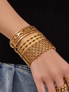 Close-up of gold layered bracelet set with leaf cutouts and textured bangles for women
