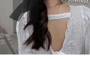 Close-up of black gauze bow hair clip styled with elegant half-up bun on model