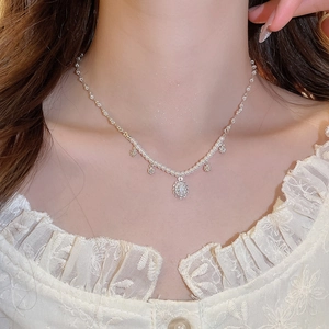 Detail of silver pearl necklace with floral pendant worn by model for elegant styling