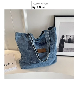 Macro detail of washed light blue denim tote bag with leather logo patch and pocket