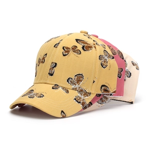 Détail de trois casquettes de baseball en coton avec imprimés papillons multicolores