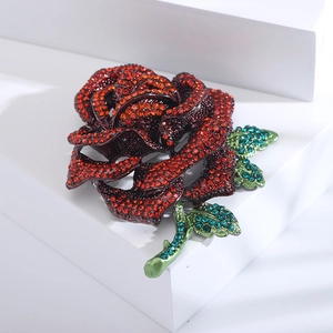 Detailed view of luxury rose brooch with red and green rhinestones on dark alloy