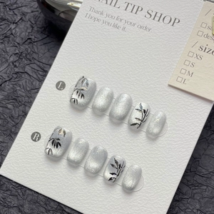Silver cat-eye press-on nails featuring hand-painted black bamboo leaves pattern