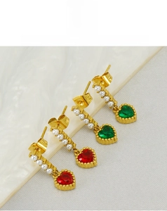 Macro detail of heart-shaped zircon earrings with vertical pearl inlay in gold finish