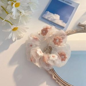 Detail of white organza scrunchie with pink floral embroidery and elegant texture