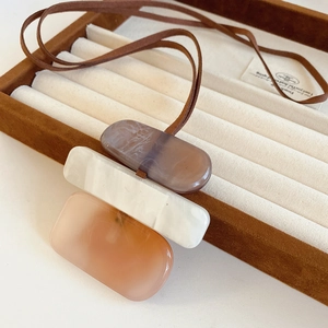 Detail of square resin pendants in brown and cream colors on a brown leather cord