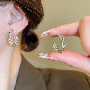 Detailed close-up of C-shaped chain stud earrings with sparkling pavé cubic zirconia