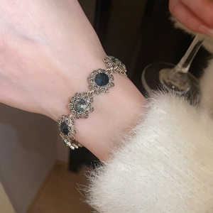 Close-up of vintage floral bracelet with blue gemstones and diamonds on a model's wrist
