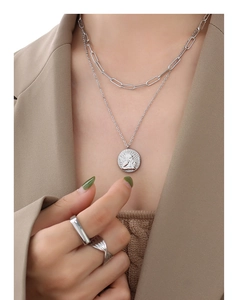Detail of silver angel pendant double layer necklace with two textured rings on a model