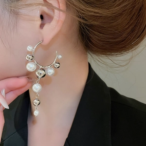 Detail view of pearl tassel C-shaped earrings worn by a model in soft lighting