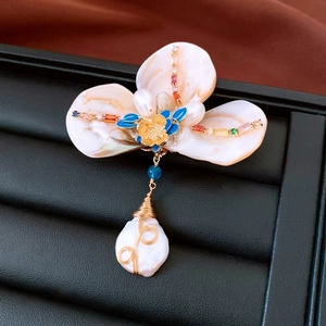 Macro detail of fan-shaped pearl brooch with shell petals and gold-plated zircon inlay