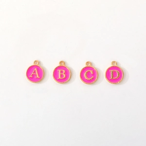 Detail of A B C D alphabet charms with pink enamel and gold finish for DIY jewelry