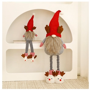 Close-up of plush red and grey Christmas gnomes with reindeer antlers on soft fabric