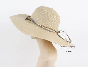 Detail of light beige woven straw hat featuring dual-tone cord and star pendant