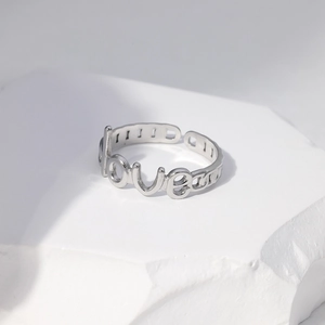 Macro shot of silver-tone adjustable ring featuring love lettering and chain design
