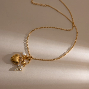 Détail du collier en or 18K avec pendentif cœur, croix en strass et perle élégante