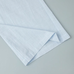 Detailed macro view showing the natural cotton linen texture and hem of the blue trousers