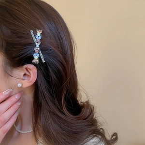 Vue détaillée de la barrette en strass de luxe portée sur des cheveux bruns ondulés