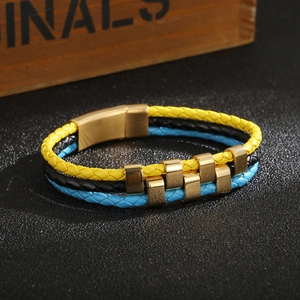 Detail of multi-layer leather braided bracelet with gold magnetic clasp on black surface