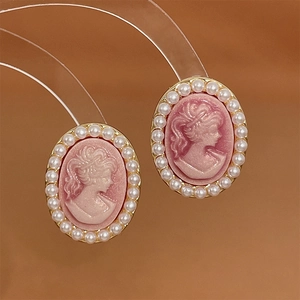 Close-up of vintage oval earrings with pink relief portrait and small pearl border