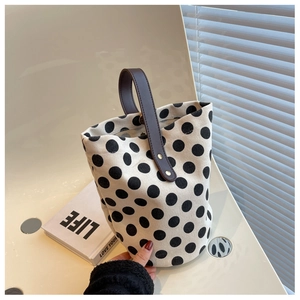 Detail of polka dot canvas bucket bag with brown leather handles and metal rivets