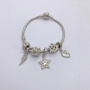Close-up of silver snake chain bracelet with zircon star and crown charms