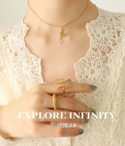 Detail of butterfly pendant necklace and gold rings worn with white lace clothing