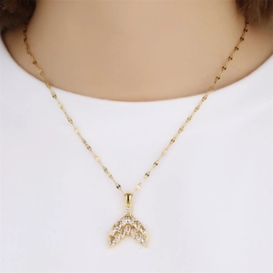 Close-up of gold fishtail pendant necklace with inlaid cubic zirconia on a model neck