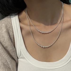Close-up of a double-layer long pearl necklace with gradient white beads on a model
