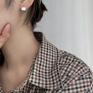 Close-up of minimalist square silver hoop earrings worn by a model in casual attire