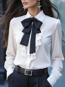 Detail of white blouse featuring a large black bow tie and elegant ruffle trim design