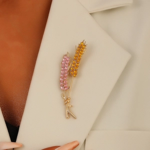 Elegant wheat ear brooch with pink and yellow rhinestones on a beige suit lapel