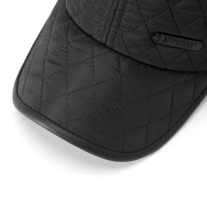 Detail of black quilted baseball cap with metal brand plate and leather-wrapped brim