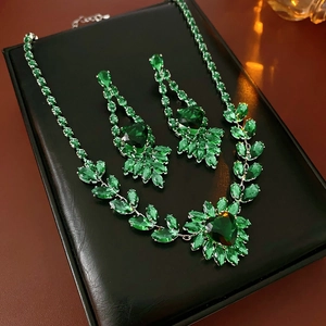 Close-up of emerald green jewelry set with necklace and earrings on black leather